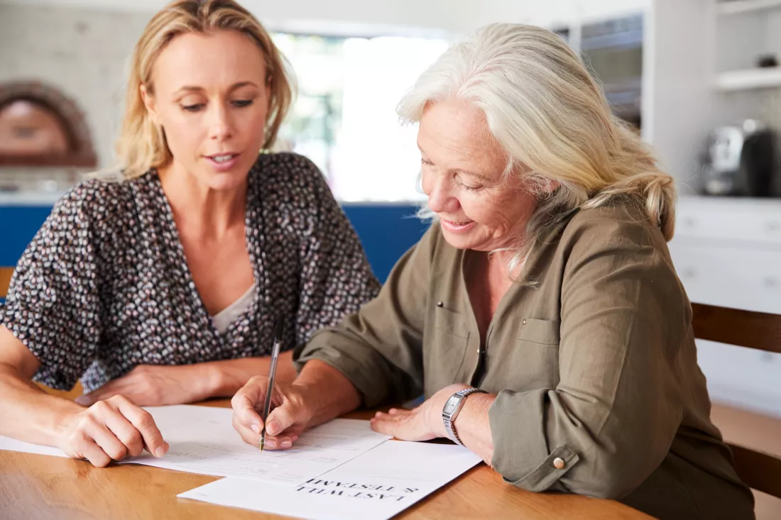 female-friend-helping-senior-woman-complete-last-will-testament-home